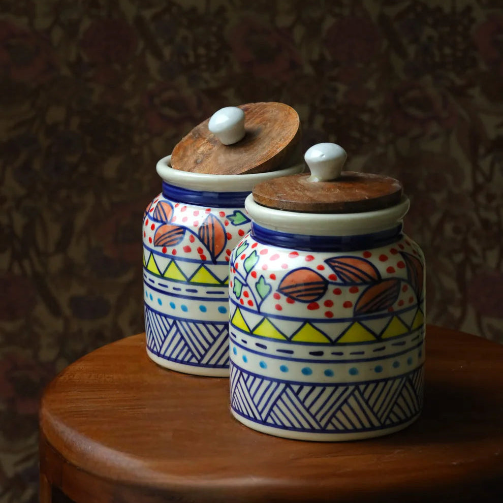Two ceramic jars with colorful patterns on a wooden surface against a dark textured background
