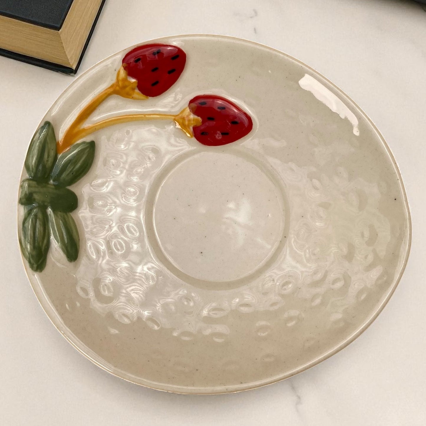 Ceramic plate with strawberry design on a marble surface