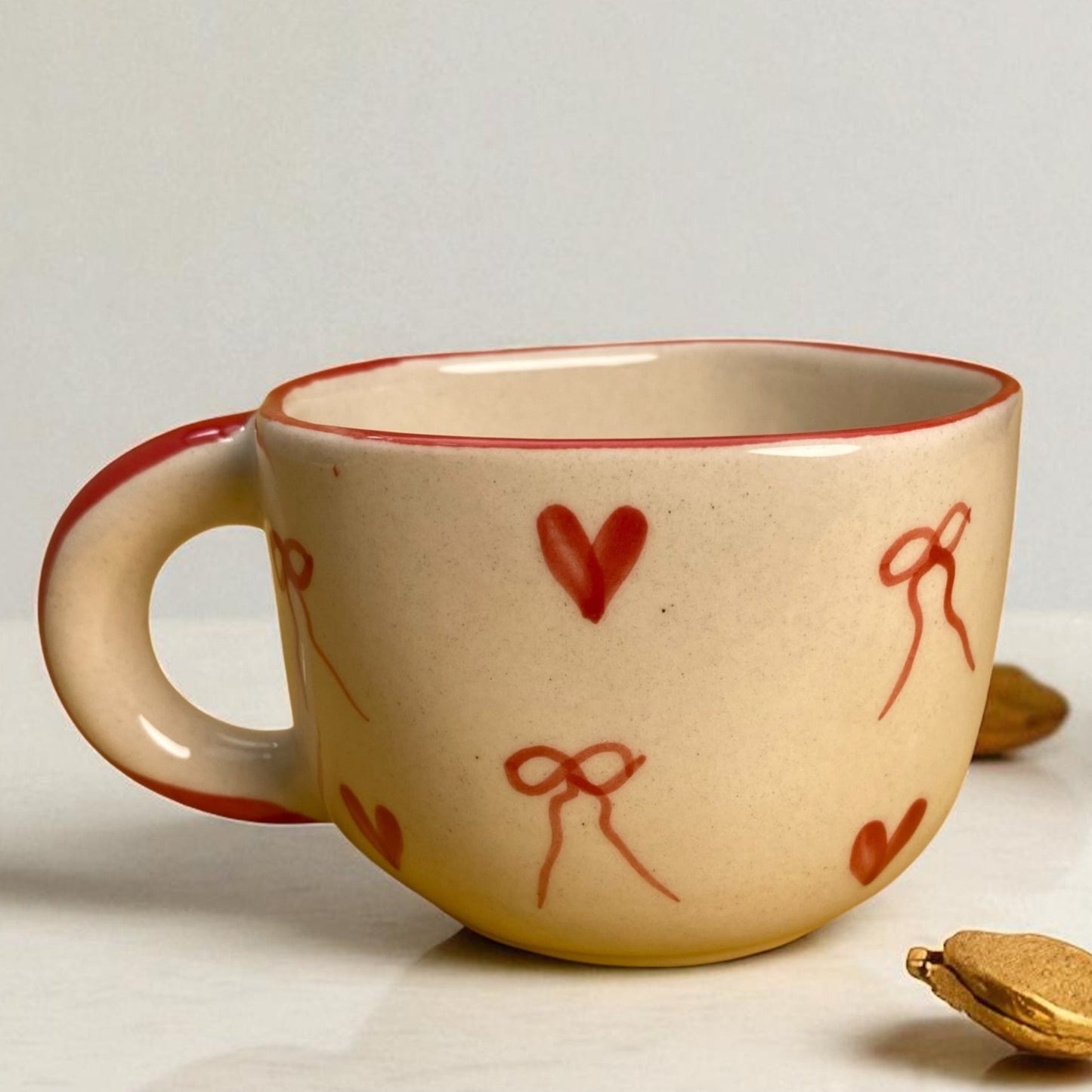 Ceramic mug with red heart and bow designs on a white surface