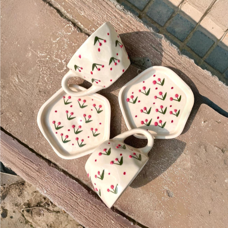 Set of ceramic cups and saucers with floral design on a textured surface