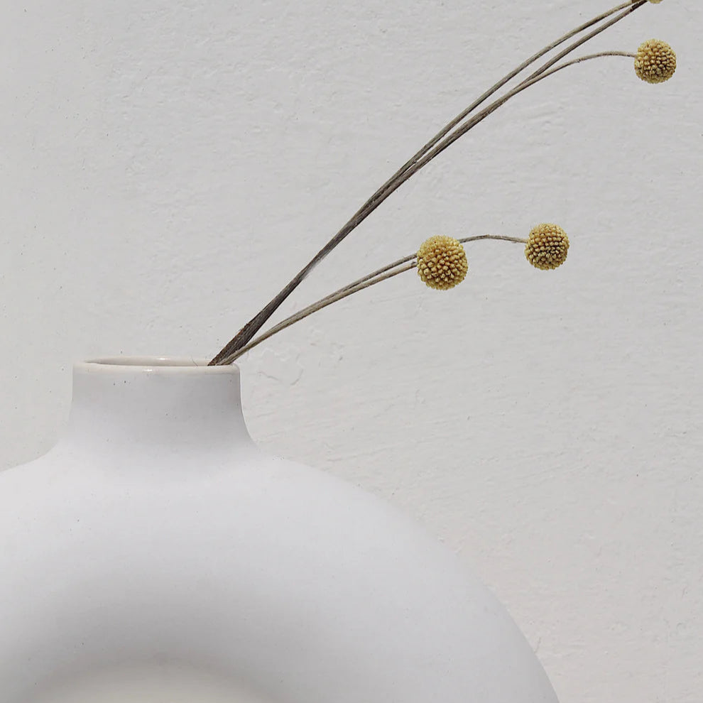 White vase with a branch on a light gray background