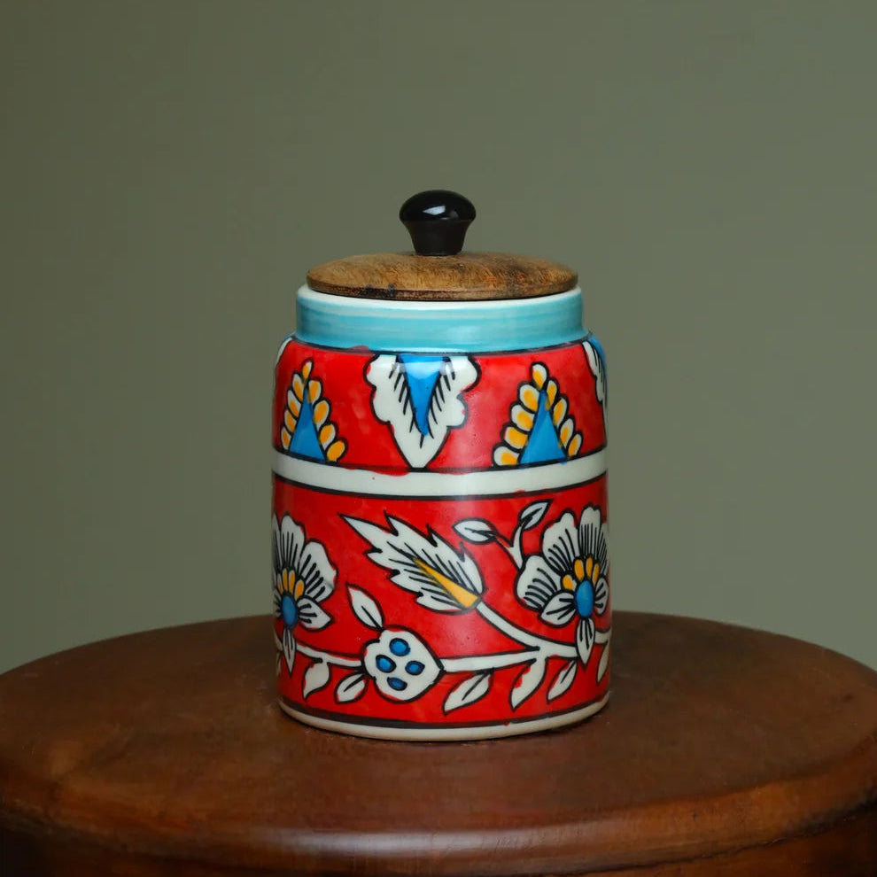 Decorative ceramic jar with floral patterns on a wooden surface against a plain background