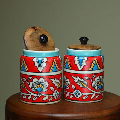 Two ceramic jars with floral patterns on a wooden surface against a plain background