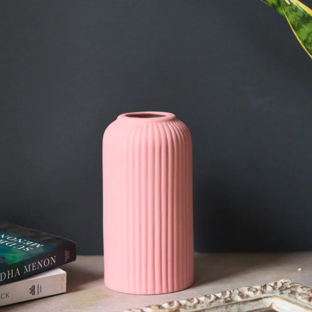 Pink ribbed vase on a surface with a dark gray background