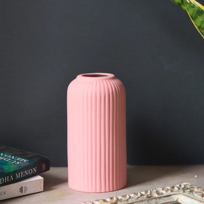 Pink ribbed vase on a surface with a dark gray background