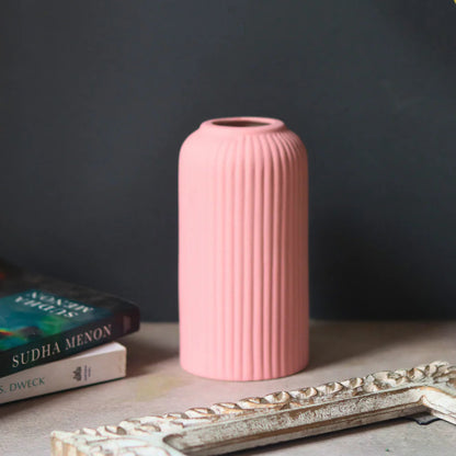 Pink ribbed vase on a surface with a dark gray background