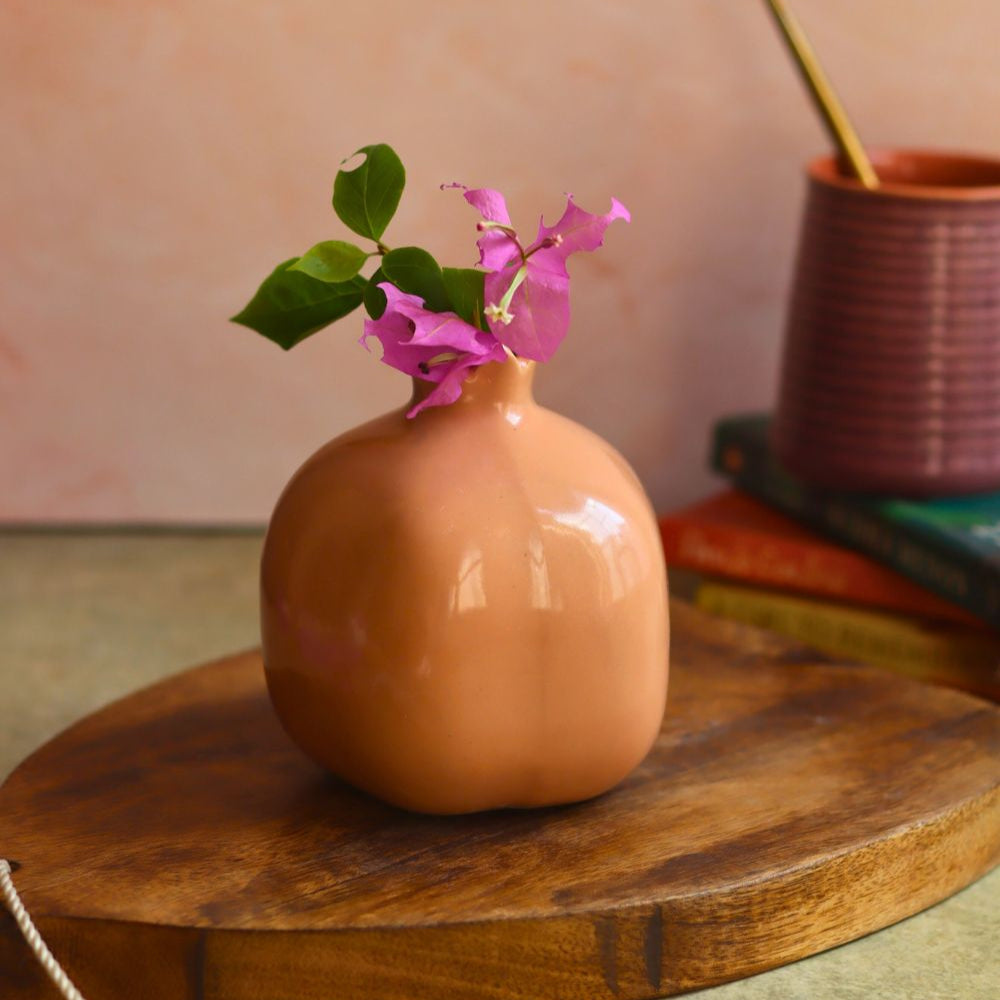 Brown ceramic vase with flowers on a wooden surface