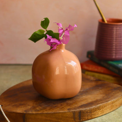 Brown ceramic vase with flowers on a wooden surface