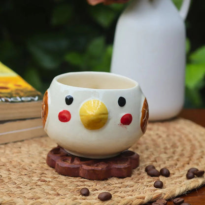 Ceramic chicken-shaped mug on a woven mat with coffee beans and a blurred background