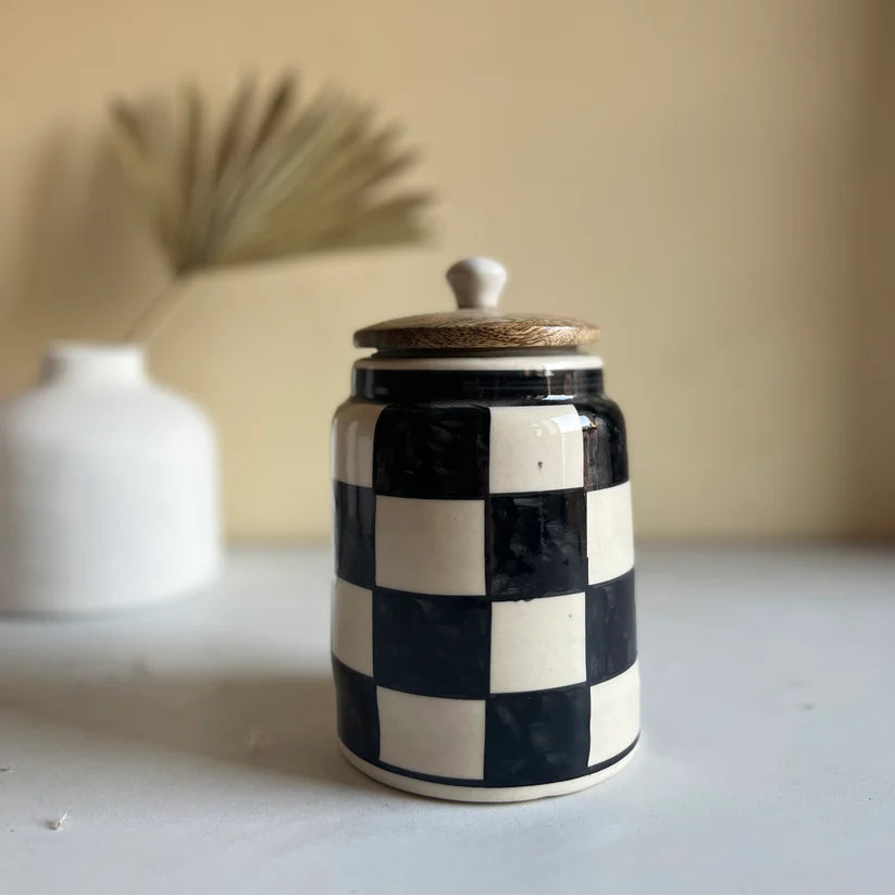Ceramic jar with black and white checkered pattern on a neutral background