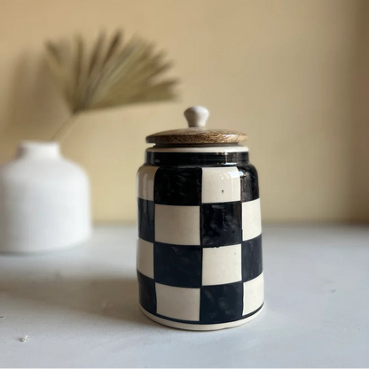 Ceramic jar with black and white checkered pattern on a neutral background