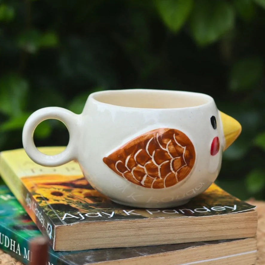 Chicken-shaped mug on a stack of books with a blurred green leafy background