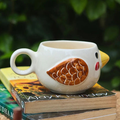 Chicken-shaped mug on a stack of books with a blurred green leafy background