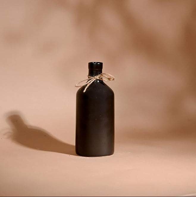 Black bottle with a string on a beige background