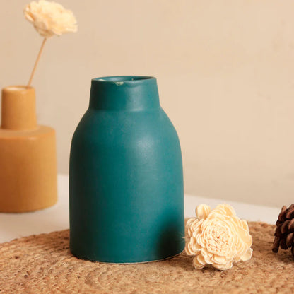 Teal vase on a textured surface with a beige background
