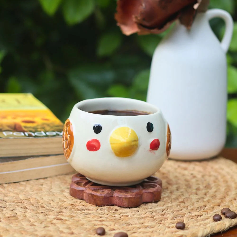 Ceramic cup shaped like a chicken with coffee on a woven surface with a blurred natural background