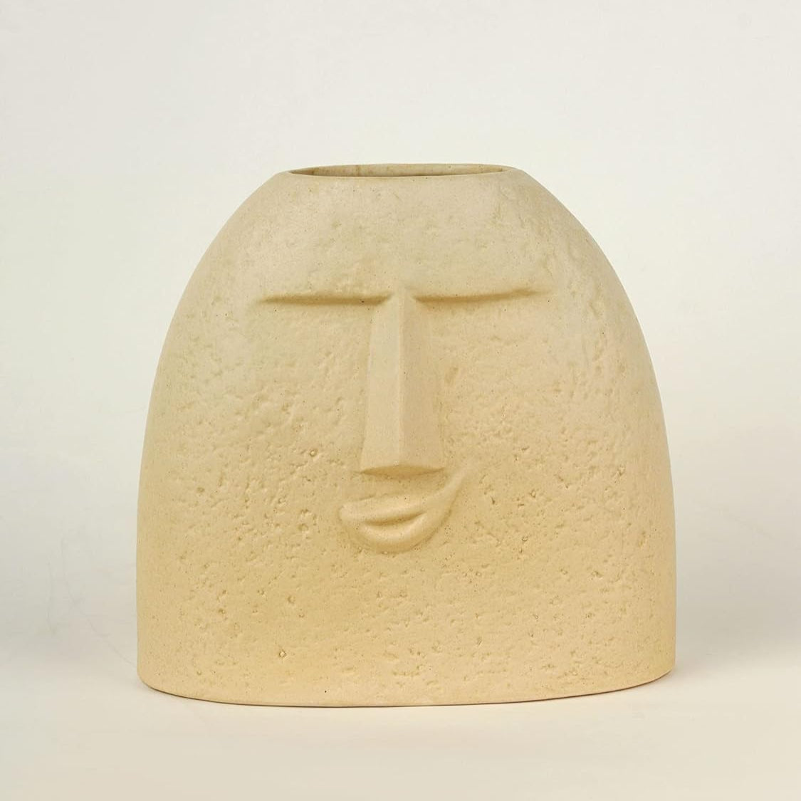 Beige ceramic vase with face design on a light beige background