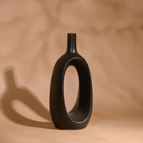 Black vase with unique design on a beige background