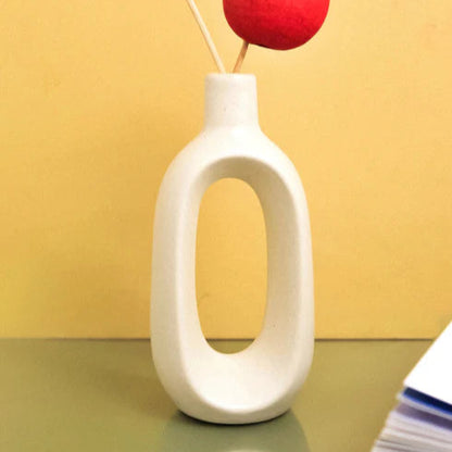 White vase with a red flower against a yellow background