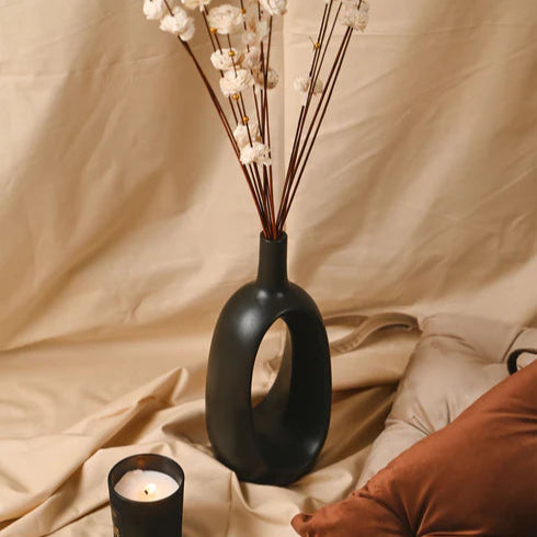 Black vase with decorative elements on a beige fabric background