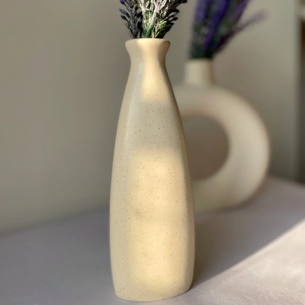 Beige ceramic vase with lavender on a light surface