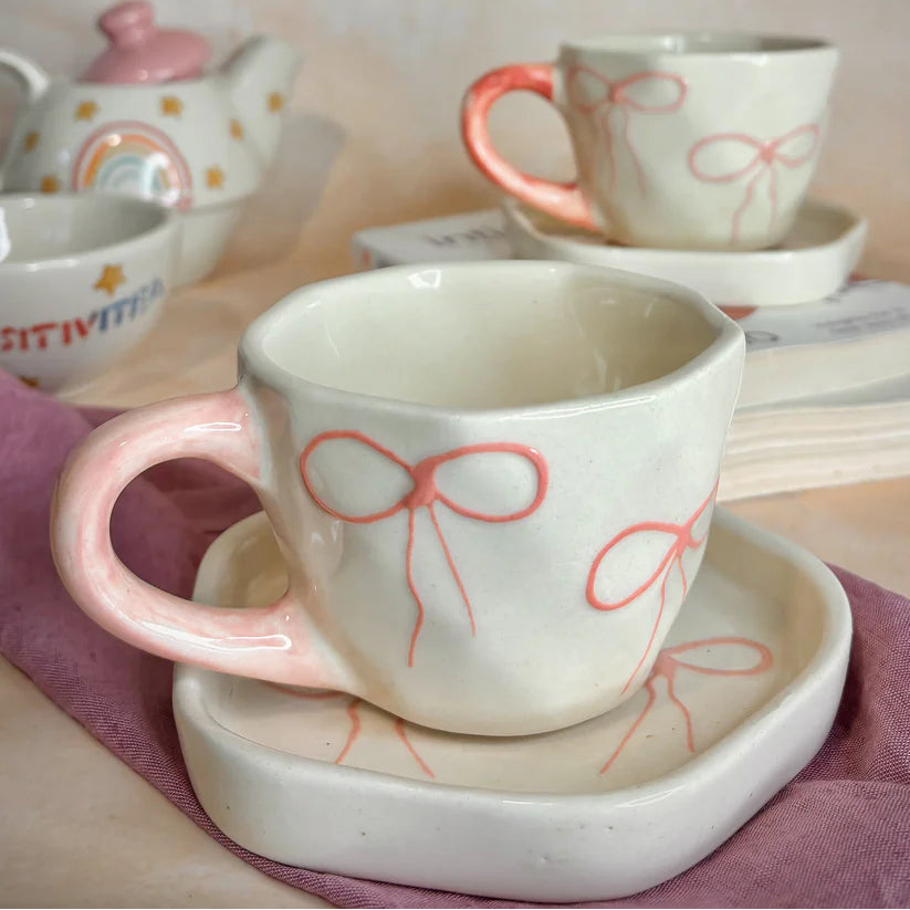 Ceramic cups with bow designs on a pink cloth