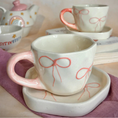 Ceramic cups with bow designs on a pink cloth