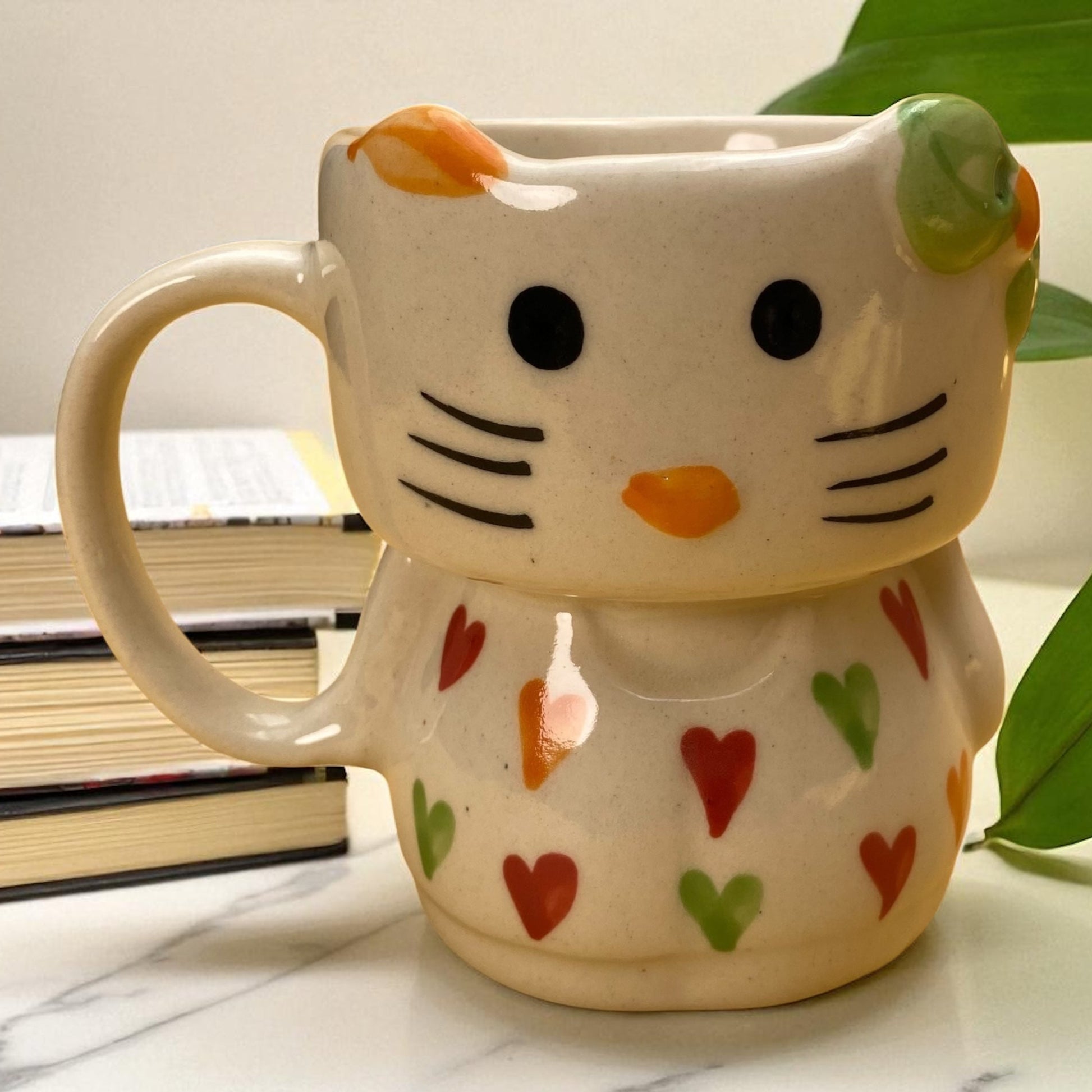 Cat-shaped mug with heart patterns on a marble surface