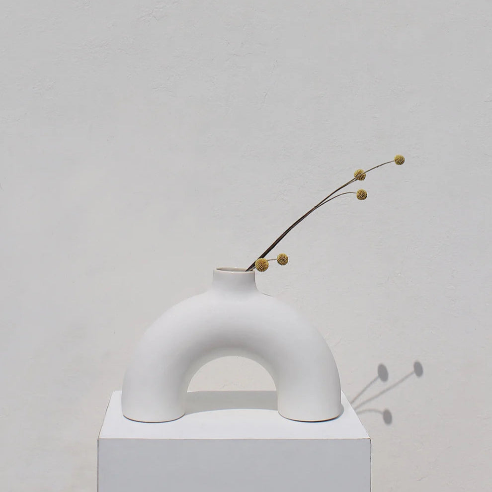 Minimalist white vase with a branch on a light gray background