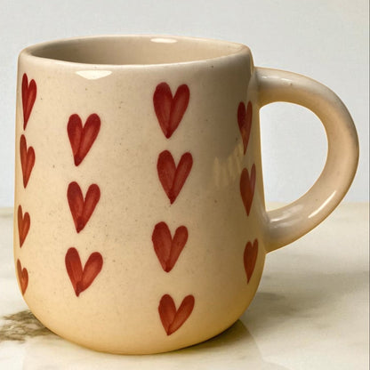 Ceramic mug with red heart patterns on a light background