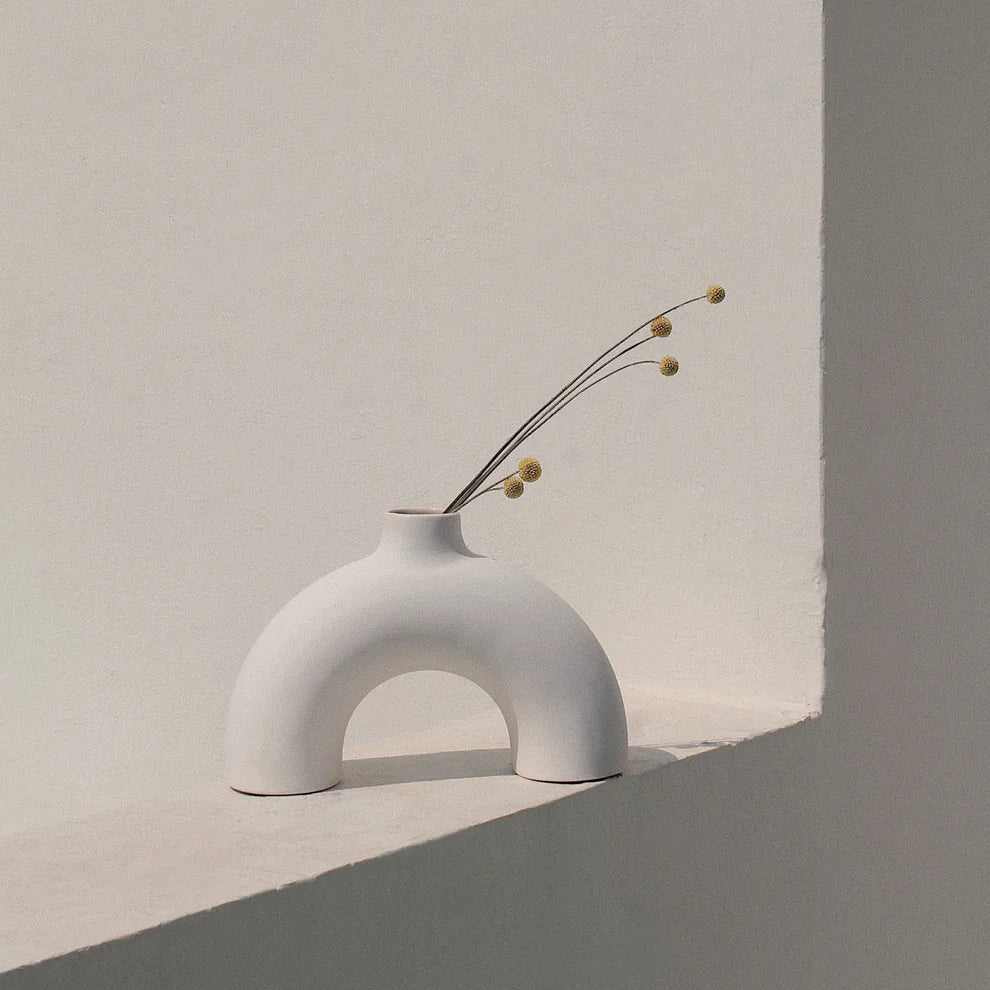 Minimalist white vase with dried flowers against a neutral background