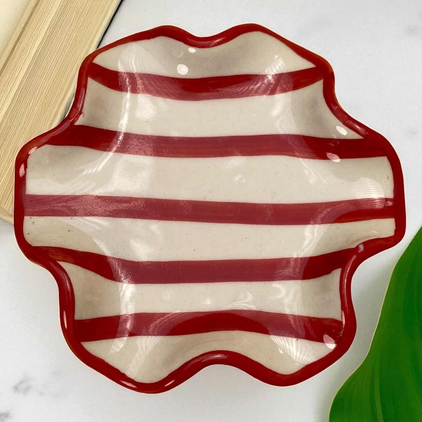Ceramic dish with red and white striped pattern on a marble surface