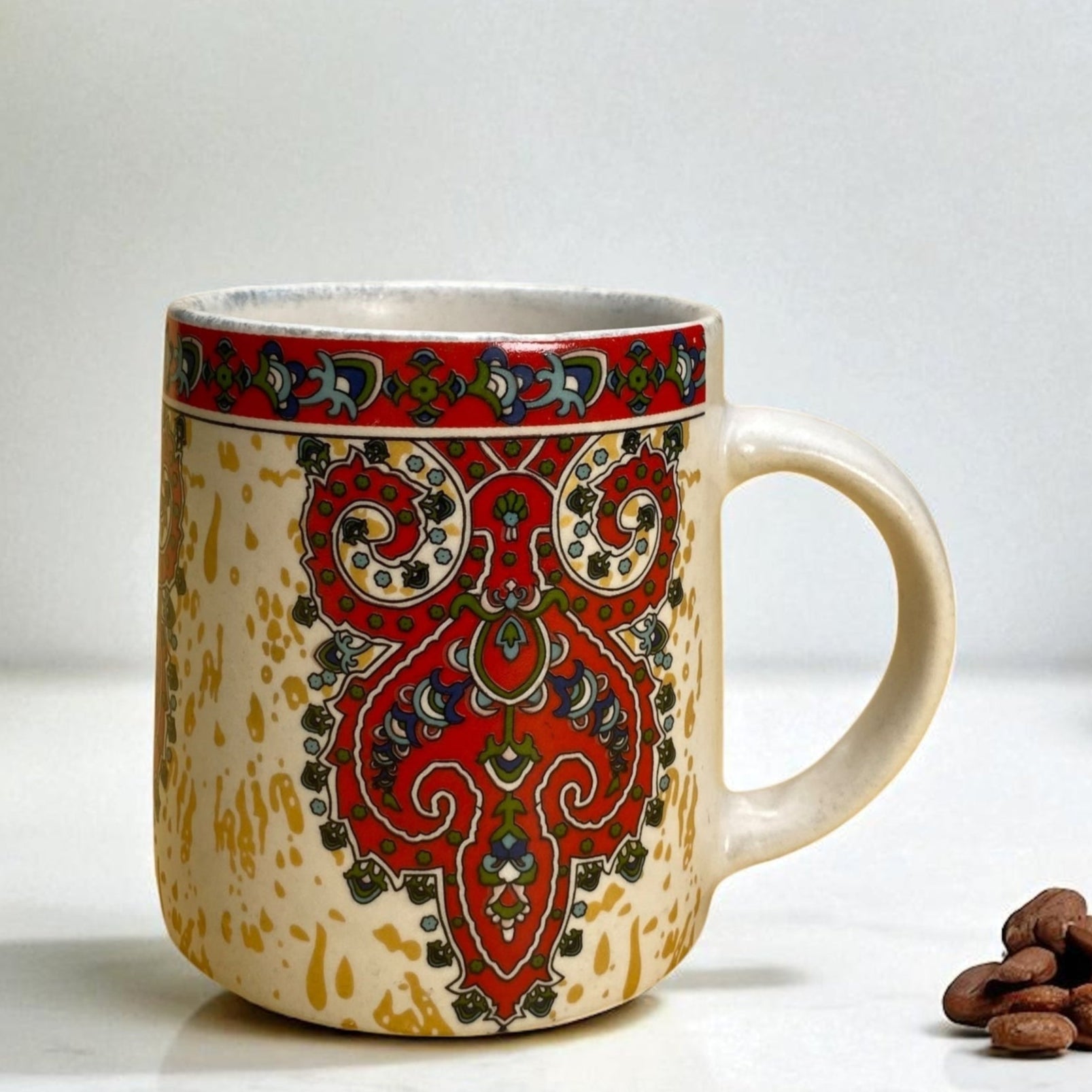 Decorative mug with intricate red and green patterns on a white background