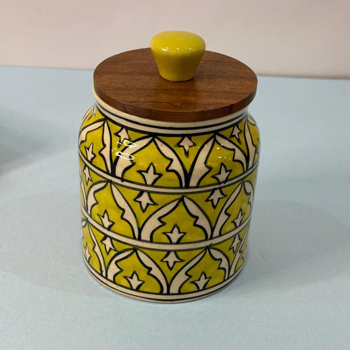 Yellow ceramic jar with a wooden lid on a white background