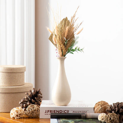 Decorative items including a vase with dried plants, books, and decorative boxes on a wooden surface.