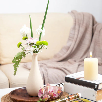 Decorative setup on a coffee table with a vase, books, and candles in a living room.
