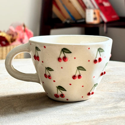 Ceramic mug with cherry design on a wooden surface