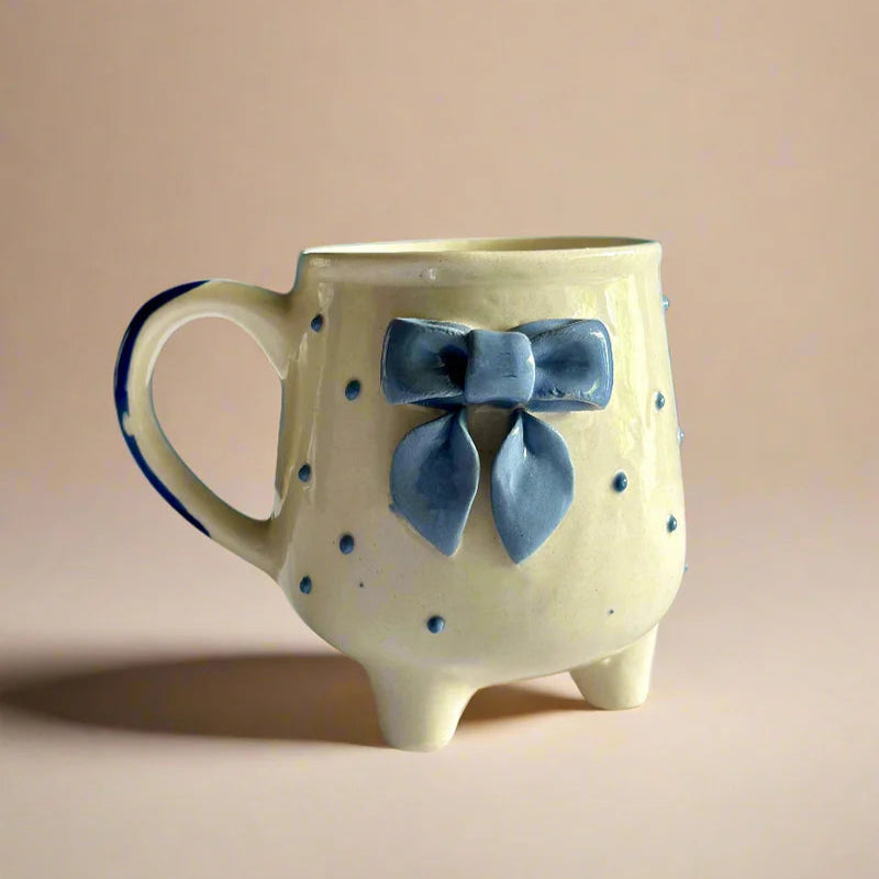 Ceramic mug with a blue bow on a beige background