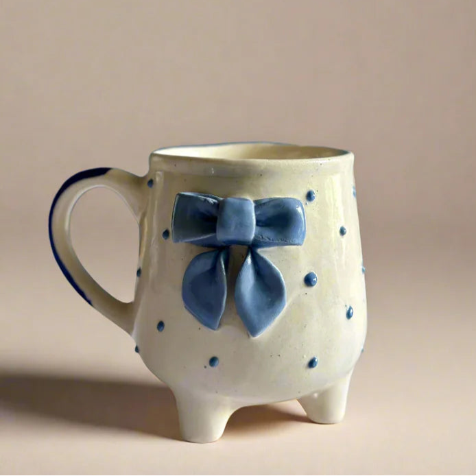Ceramic mug with a blue bow on a beige background