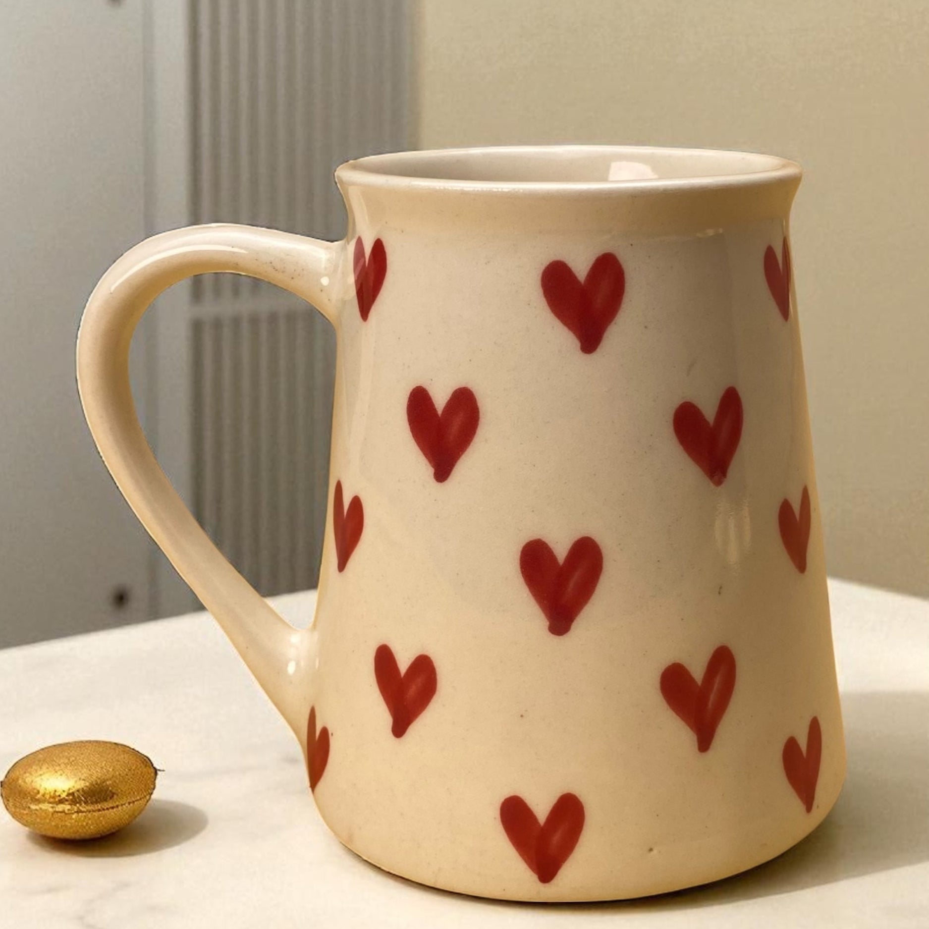 White mug with red heart patterns on a light surface