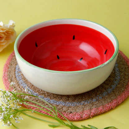 White bowl with red interior and black seeds on a textured mat with yellow background