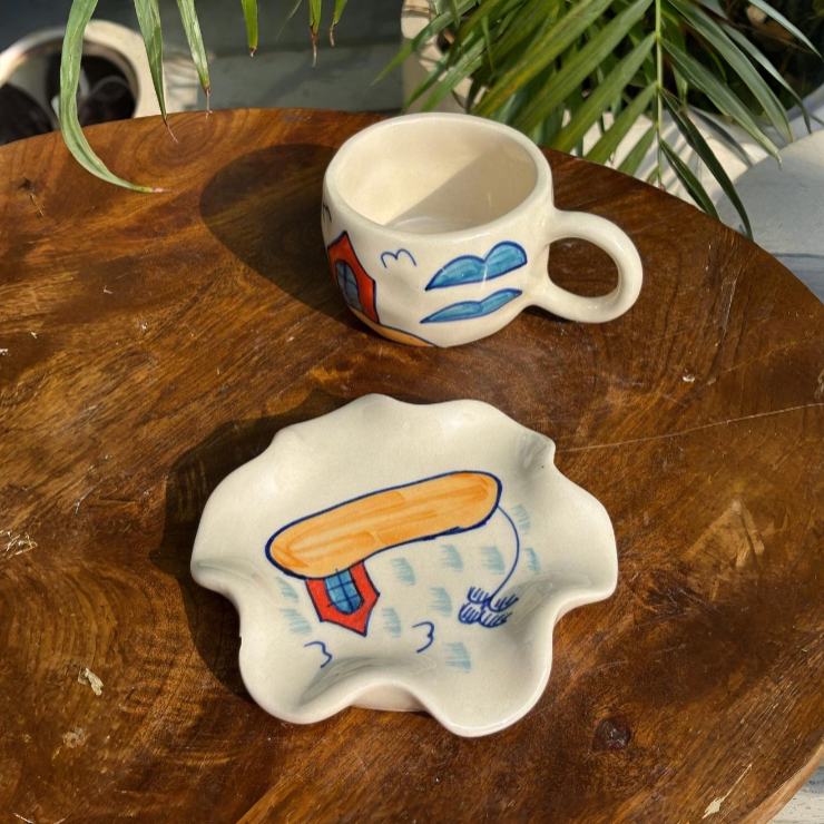 Two ceramic items with artistic designs on a wooden surface.