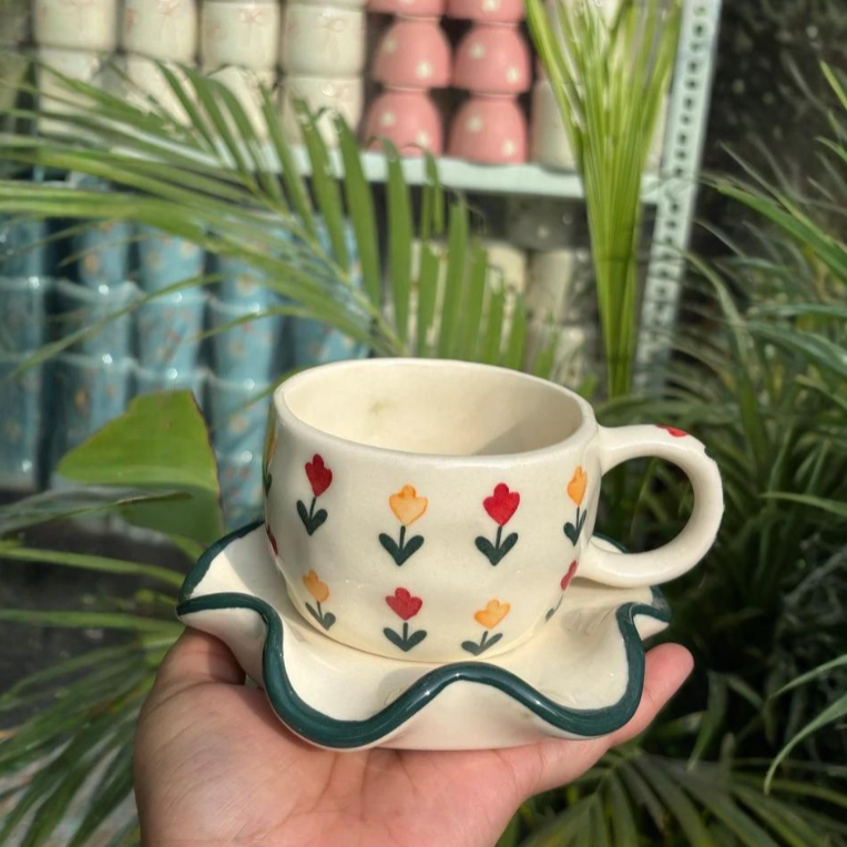 Ceramic cup with floral design held in a hand against a plant background