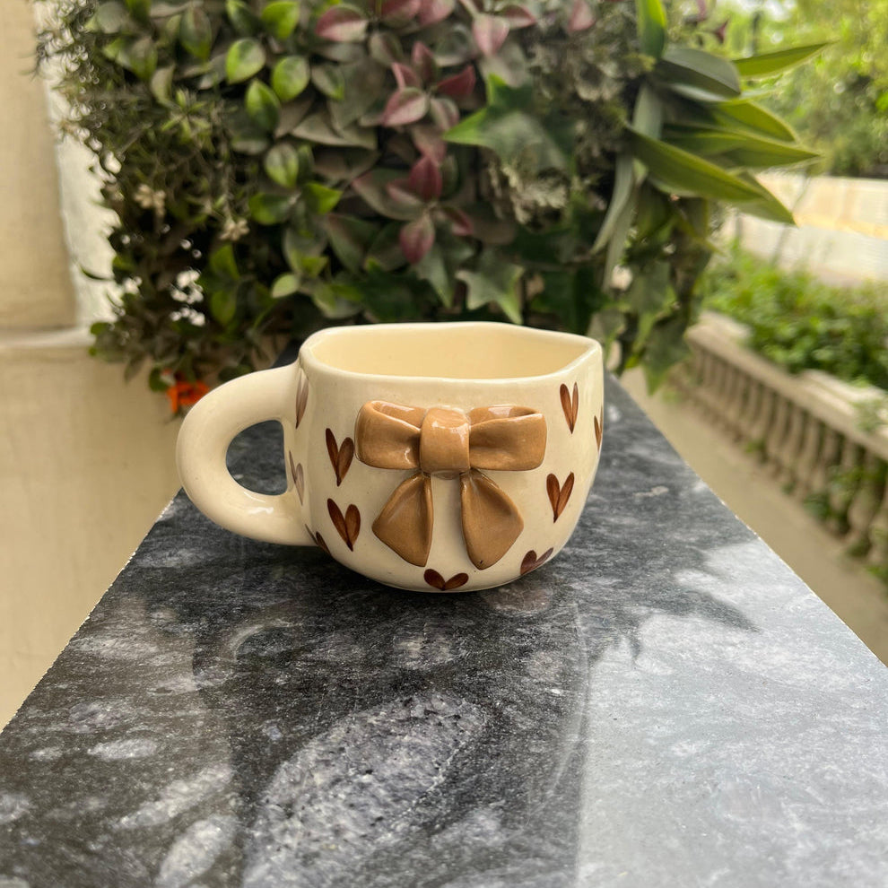Ceramic mug with bow design on a stone surface outdoors