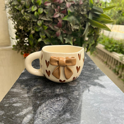 Ceramic mug with bow design on a stone surface outdoors