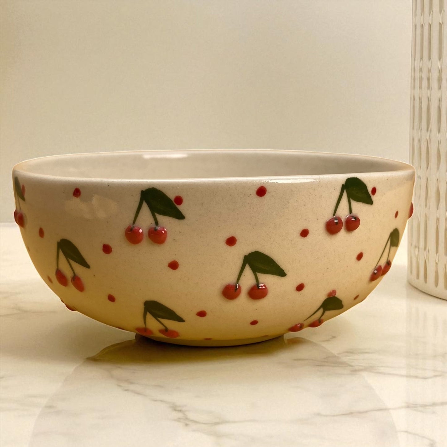 Ceramic bowl with cherry design on a marble surface